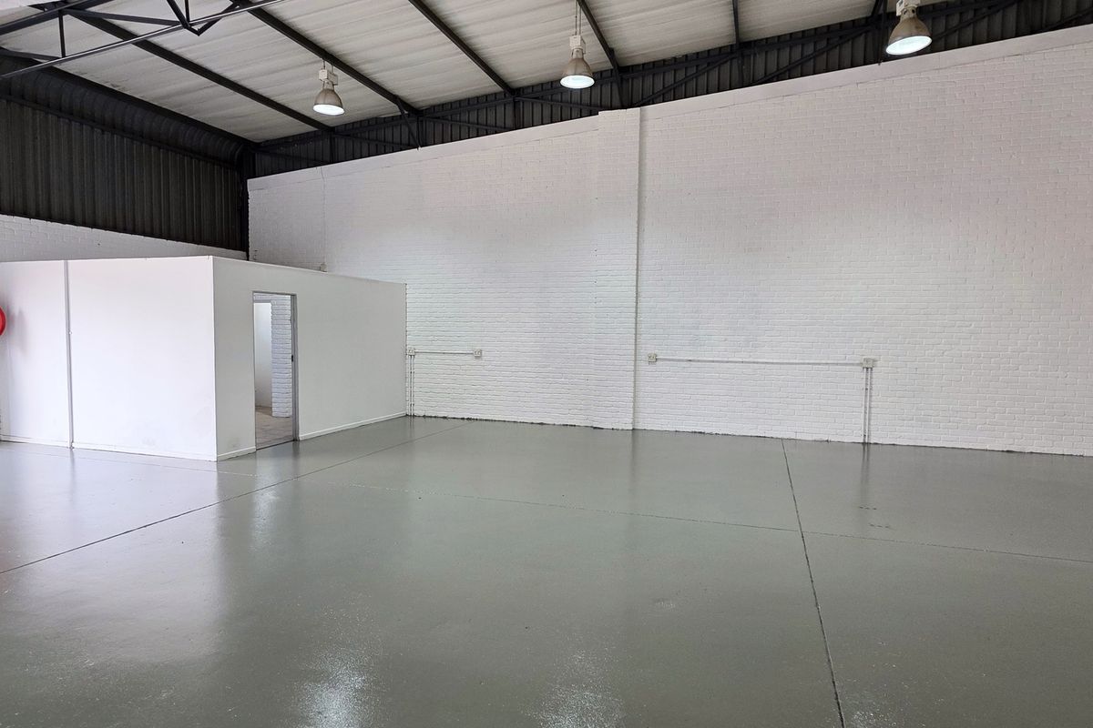 Spacious industrial warehouse unit featuring polished epoxy flooring, high exposed ceilings with pendant lighting, and a dedicated internal partitioned office space.