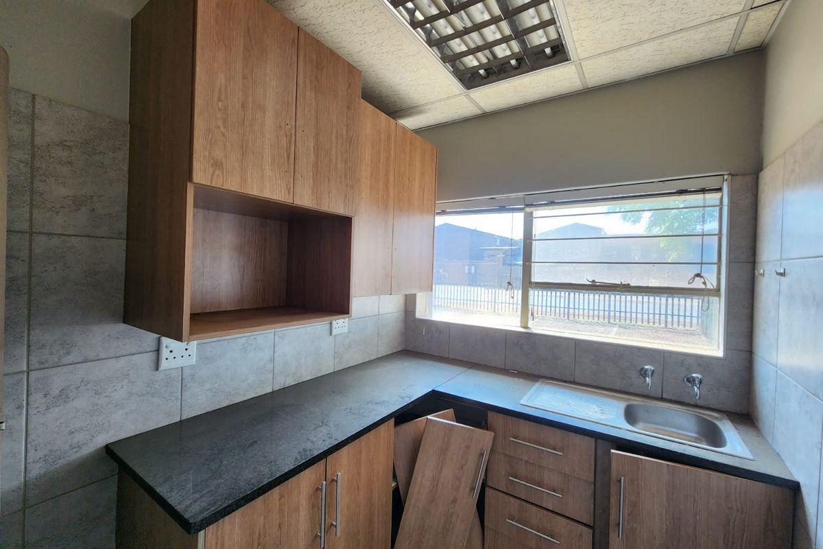 A functional kitchen space featuring laminate cabinetry, stone countertops, and a stainless steel sink, currently requiring minor repairs to cabinetry and fixtures.