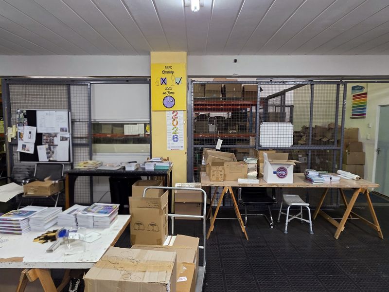 Industrial utility space featuring metal security partitions, durable rubber flooring, and functional overhead lighting, suitable for storage or workshop operations.