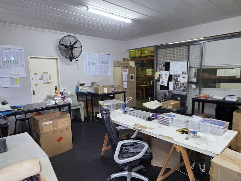 Industrial utility or workshop space featuring durable rubberized flooring, fluorescent lighting, and a wall-mounted industrial fan, suitable for various operational or storage purposes.