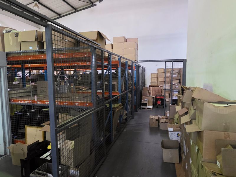 Industrial warehouse space featuring high ceilings, mezzanine storage level, and secure steel racking systems, suitable for logistics or storage operations.
