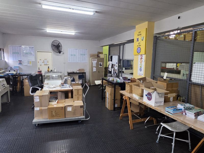 Industrial utility space featuring durable rubber flooring, fluorescent lighting, and a secure mesh partition, suitable for workshop or storage operations.
