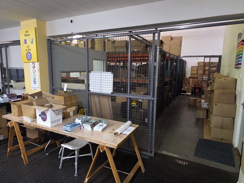 Industrial utility space featuring a secure metal cage storage area, durable rubberized flooring, and functional workspace layout suitable for storage or logistics operations.