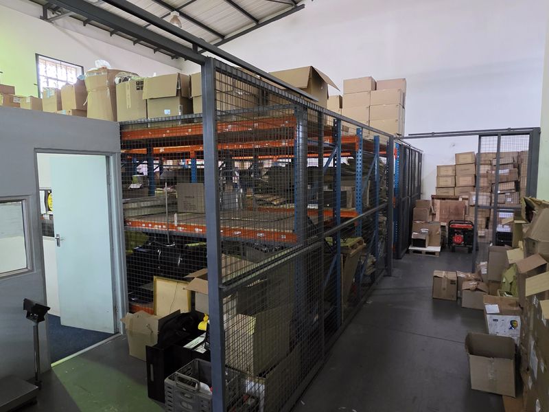 Industrial warehouse space featuring a mezzanine level, partitioned office area, and heavy-duty steel racking systems for efficient storage and operations.