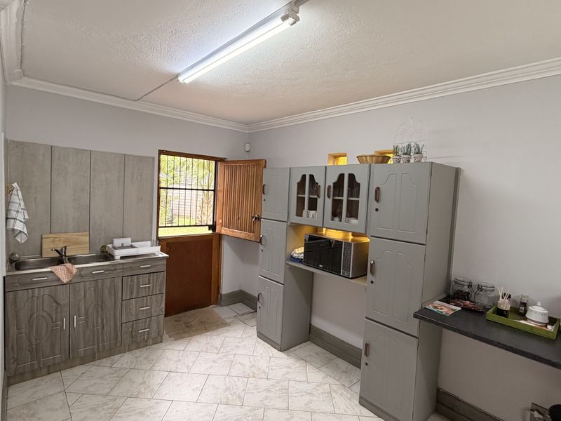 A functional kitchen area featuring built-in cabinetry, a double sink, tiled flooring, and a stable-style door providing access to the exterior.