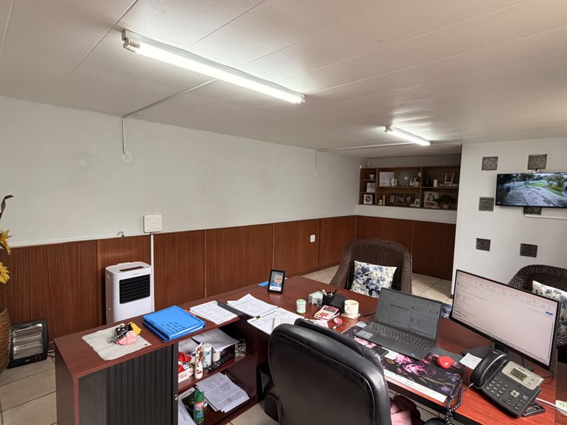 A functional office space featuring wood paneling, built-in shelving, and tiled flooring, providing a practical work environment.