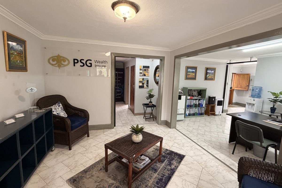 A professional office reception area featuring tiled flooring, crown molding, and clear signage, leading into an adjacent workspace.