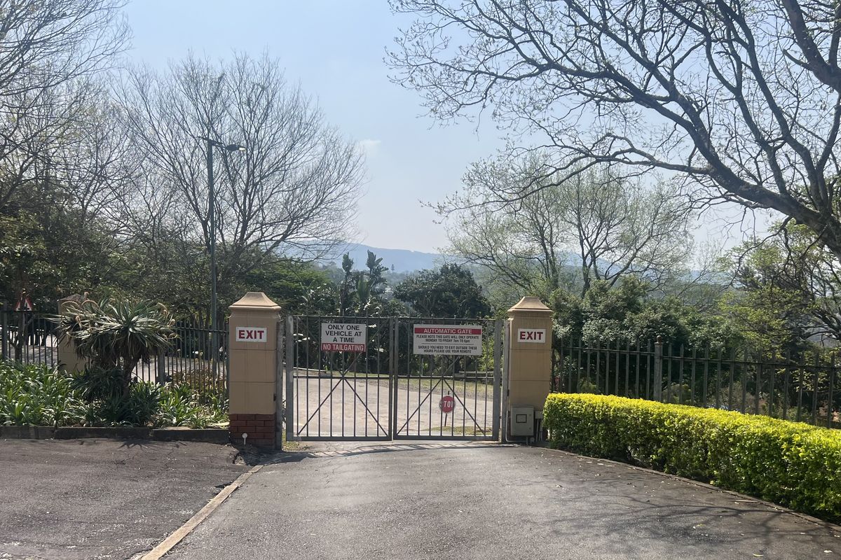 A secure automatic exit gate with metal fencing and brick pillars, providing controlled access from the office property.