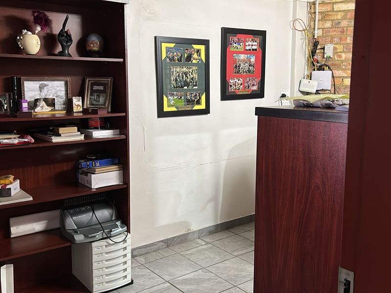 A small office or utility space featuring tiled flooring, exposed brickwork, and visible wall imperfections.