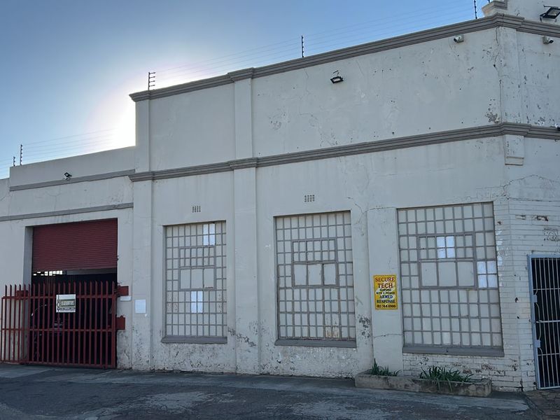 Commercial street-facing facade featuring industrial-style glass block windows, a secure roller shutter entrance, and perimeter electric fencing.