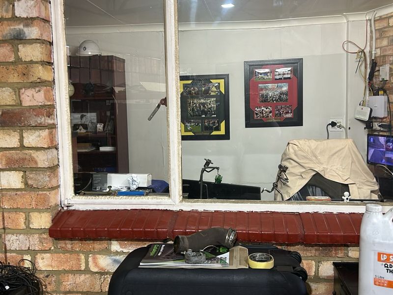 A view through an internal window into an office space featuring brick wall accents and functional electrical infrastructure.