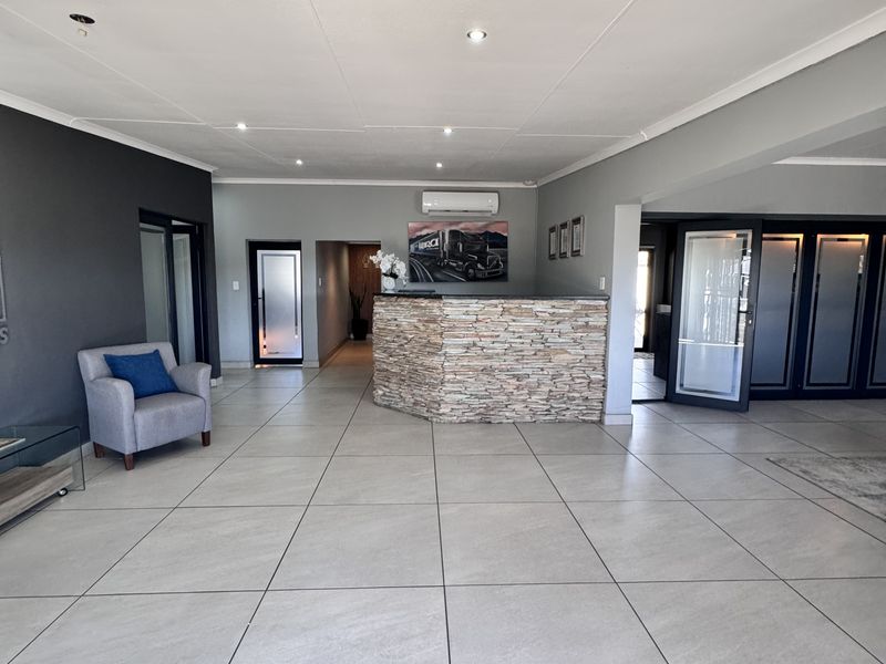 Spacious reception area featuring a stone-clad service counter, large format floor tiles, recessed lighting, and a wall-mounted air conditioning unit.