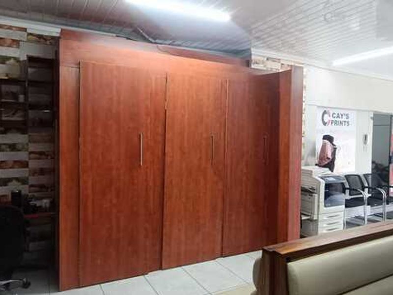 Commercial office space featuring built-in wooden cabinetry, tiled wall accents, and a functional sink area, suitable for a professional business environment.