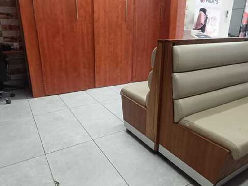 A commercial office or reception area featuring tiled flooring, built-in wooden cabinetry, and integrated bench seating.