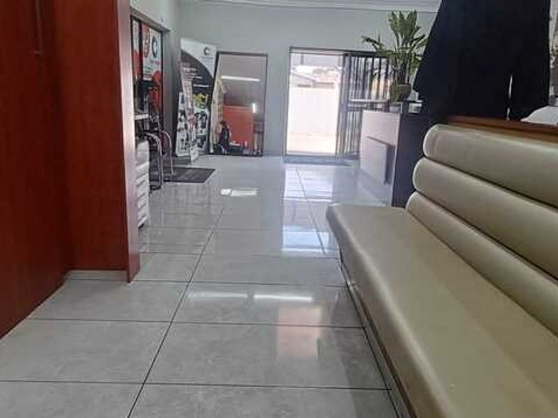 A commercial reception or waiting area featuring polished floor tiles, built-in wooden cabinetry, and a fixed seating bench.