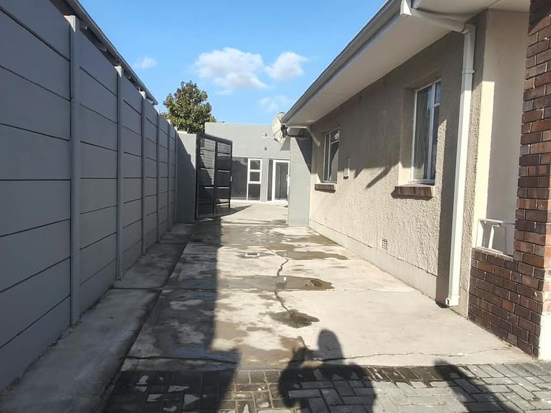 A side exterior view of the office property featuring a concrete driveway, precast boundary wall, and brick facade detailing.