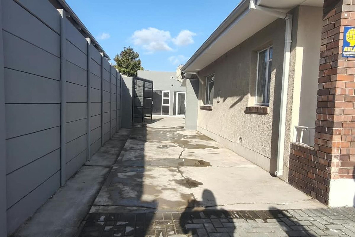 A side exterior view of the office property featuring a concrete driveway, precast boundary wall, and brick facade detailing.