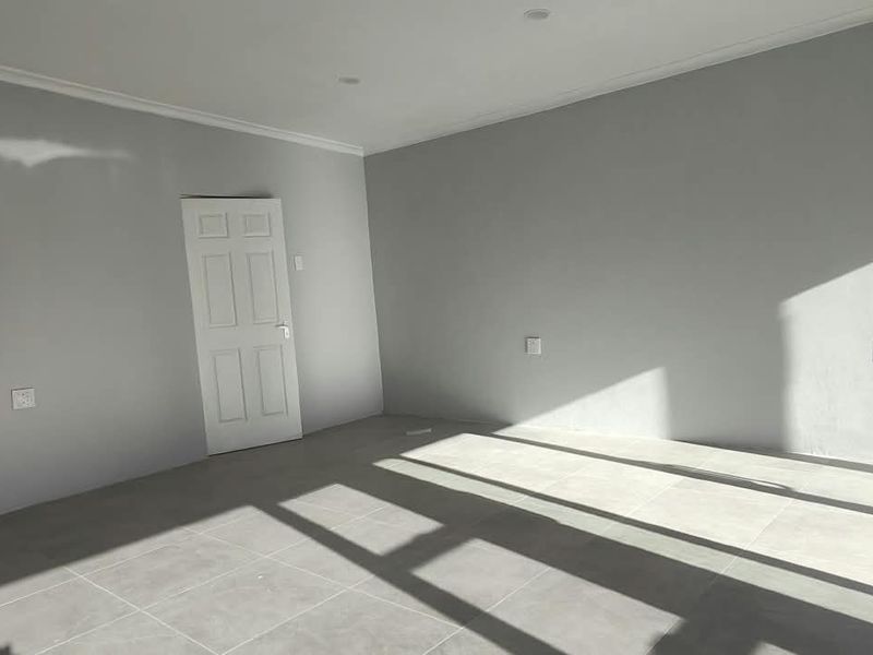 A bright, empty office space featuring neutral grey walls, tiled flooring, and recessed ceiling lighting, ready for professional fit-out.