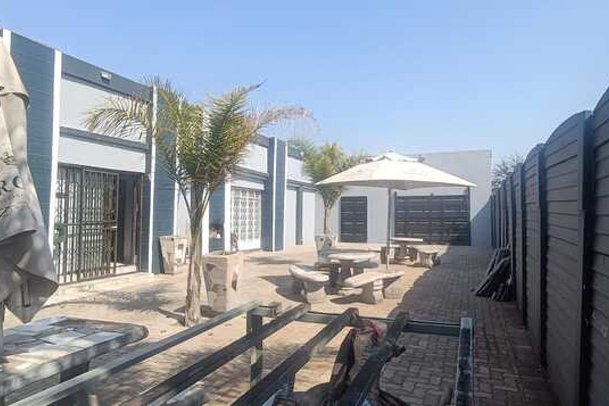 Outdoor courtyard area featuring paved flooring, perimeter fencing, and access to the main building structure.