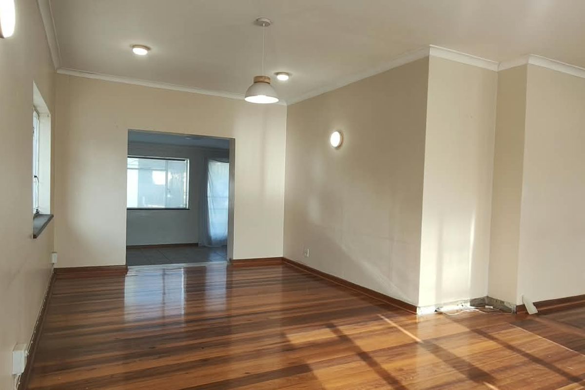 Spacious, empty office area featuring polished hardwood flooring, recessed lighting, and neutral wall finishes, offering a versatile workspace layout.