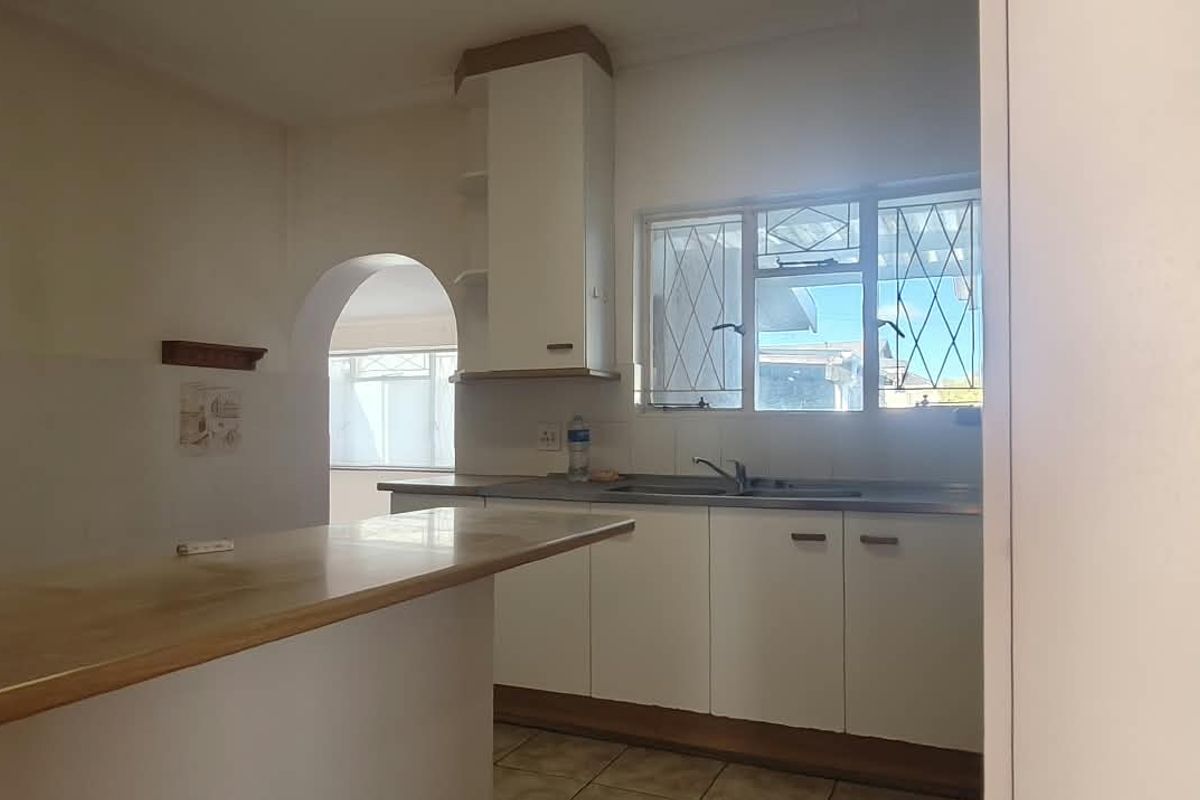 A functional kitchen featuring built-in cabinetry, a breakfast bar, and a sink, with an open archway leading to an adjacent room.