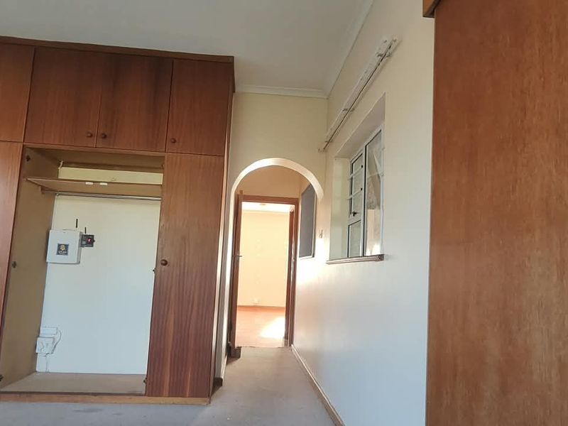 An office space featuring extensive built-in wooden cabinetry, an arched doorway, and neutral wall finishes, offering a functional layout for a professional workspace.