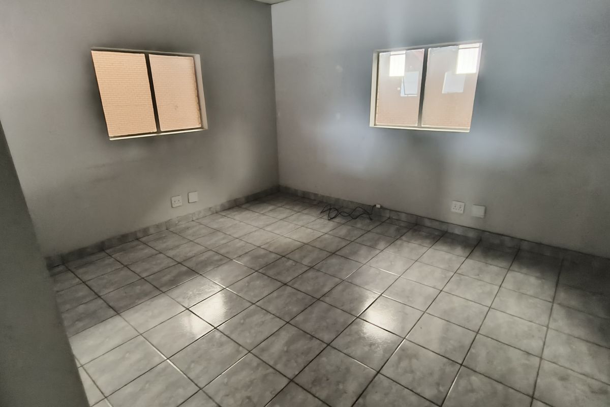 An empty bedroom featuring tiled flooring and two sliding windows, providing a blank canvas for potential industrial or office space customization.
