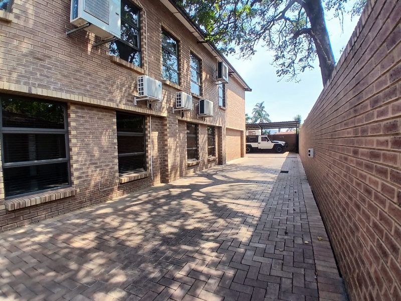 A well-maintained commercial exterior featuring a paved driveway, face brick facade, and multiple wall-mounted air conditioning units along the side of the building.