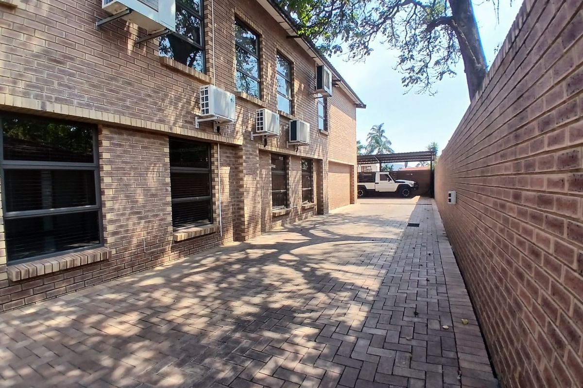 A well-maintained commercial exterior featuring a paved driveway, face brick facade, and multiple wall-mounted air conditioning units along the side of the building.
