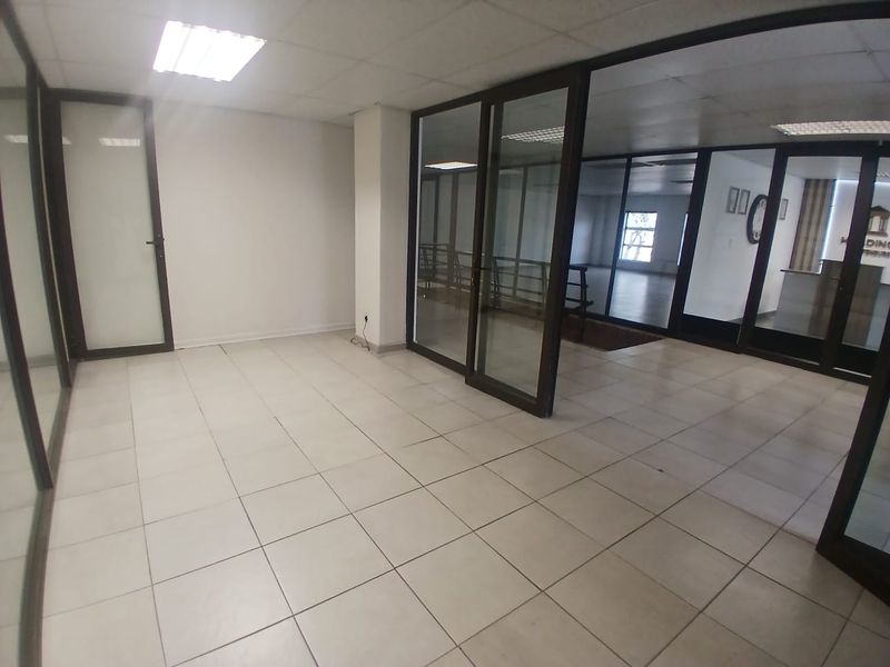 An empty office space featuring ceramic tiled flooring, suspended ceilings with recessed lighting, and modern aluminium-framed glass partitions for a professional, open-plan feel.