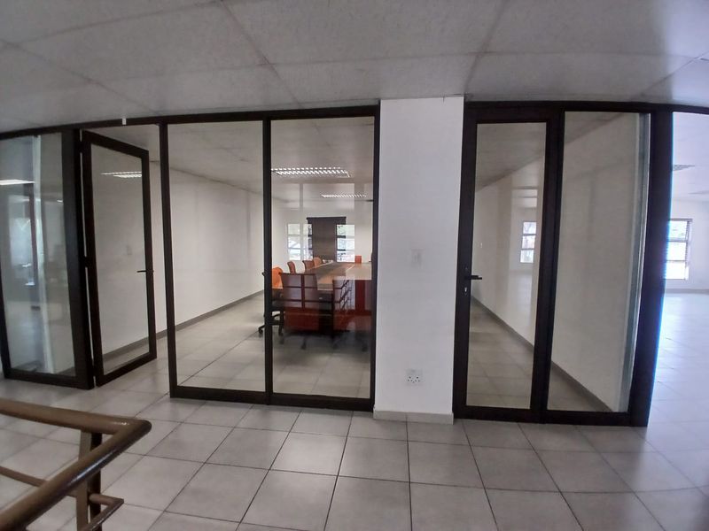 Modern office space featuring glass partition walls, aluminium frames, and tiled flooring, providing a professional and open-plan working environment.