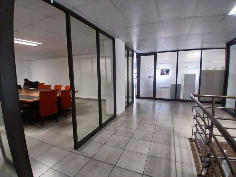 Modern office space featuring glass partition walls, tiled flooring, and a suspended ceiling, providing a professional and open work environment.