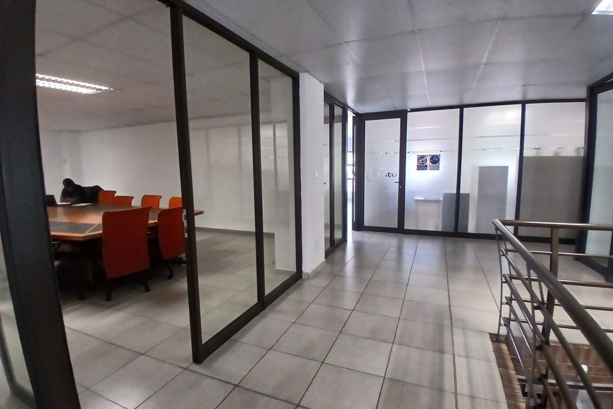 Modern office space featuring glass partition walls, tiled flooring, and a suspended ceiling, providing a professional and open work environment.