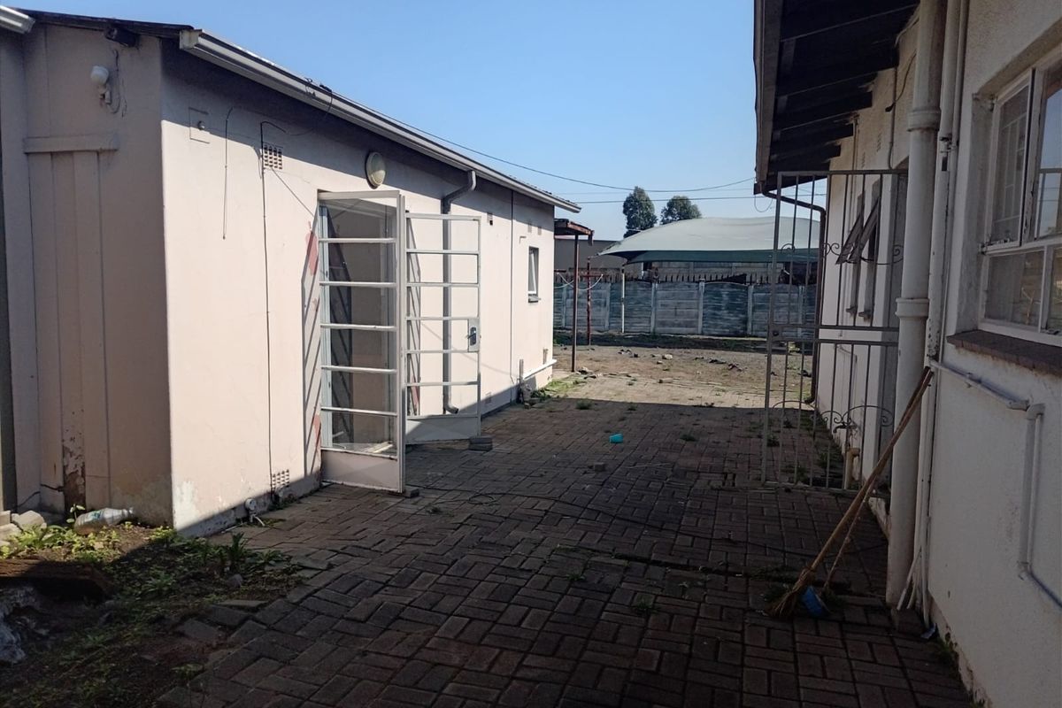Rear exterior courtyard area featuring paved flooring, security gates, and access to the building structure.