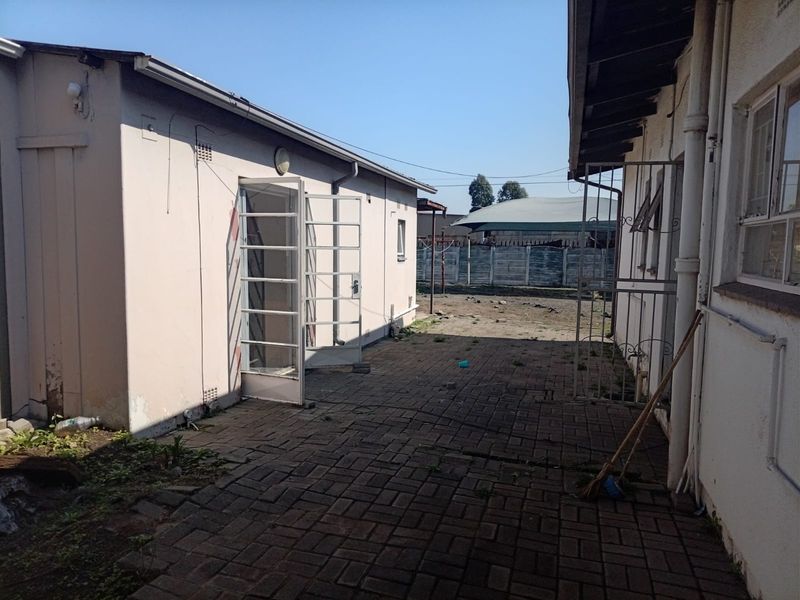 Rear exterior courtyard area featuring paved flooring, security gates, and access to the building structure.