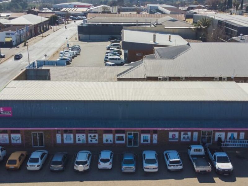 Aerial view of a commercial retail property featuring a metal roof, dedicated parking area, and multiple storefront access points.