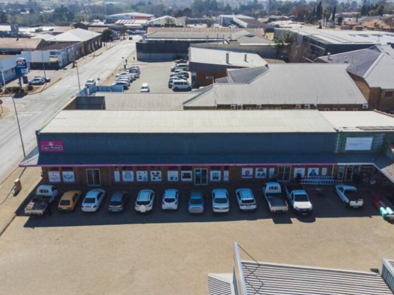 Aerial view of a commercial retail property featuring a metal roof and an extensive paved parking area for customers.