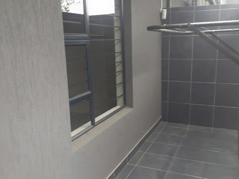 A functional outdoor laundry or utility area featuring tiled flooring, wall-mounted drying rack, and modern grey wall finishes.