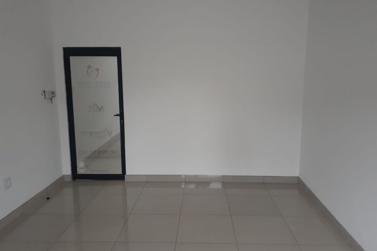 A clean, empty office space featuring neutral tiled flooring and a glass-panelled entrance door, providing a versatile environment for professional use.