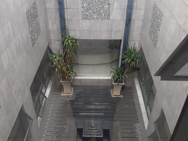An enclosed central courtyard featuring tiled walls, timber decking, and a central water feature, viewed from an elevated position.