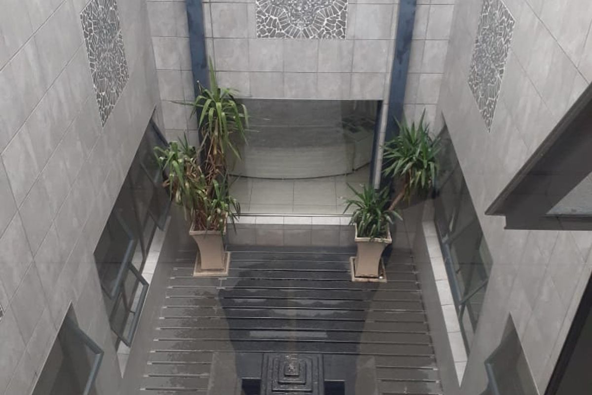 An enclosed central courtyard featuring tiled walls, timber decking, and a central water feature, viewed from an elevated position.