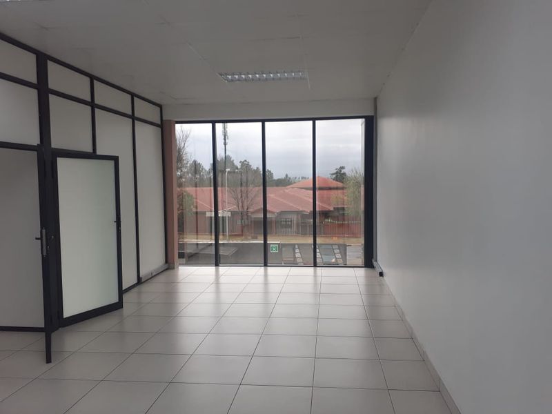 A bright, empty commercial office space featuring large floor-to-ceiling windows, tiled flooring, and modern aluminium partition frames.