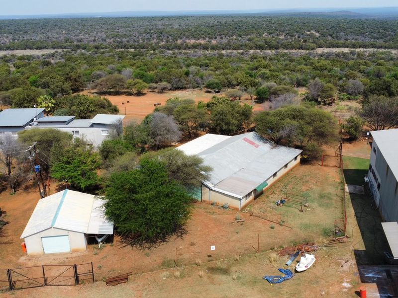 Aerial view of a farm property featuring multiple outbuildings, metal roofing, and surrounding rural landscape.
