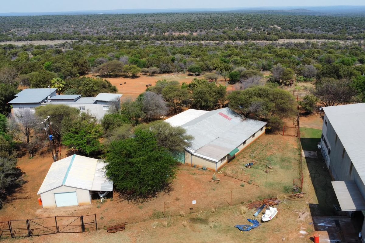 Aerial view of a farm property featuring multiple outbuildings, metal roofing, and surrounding rural landscape.