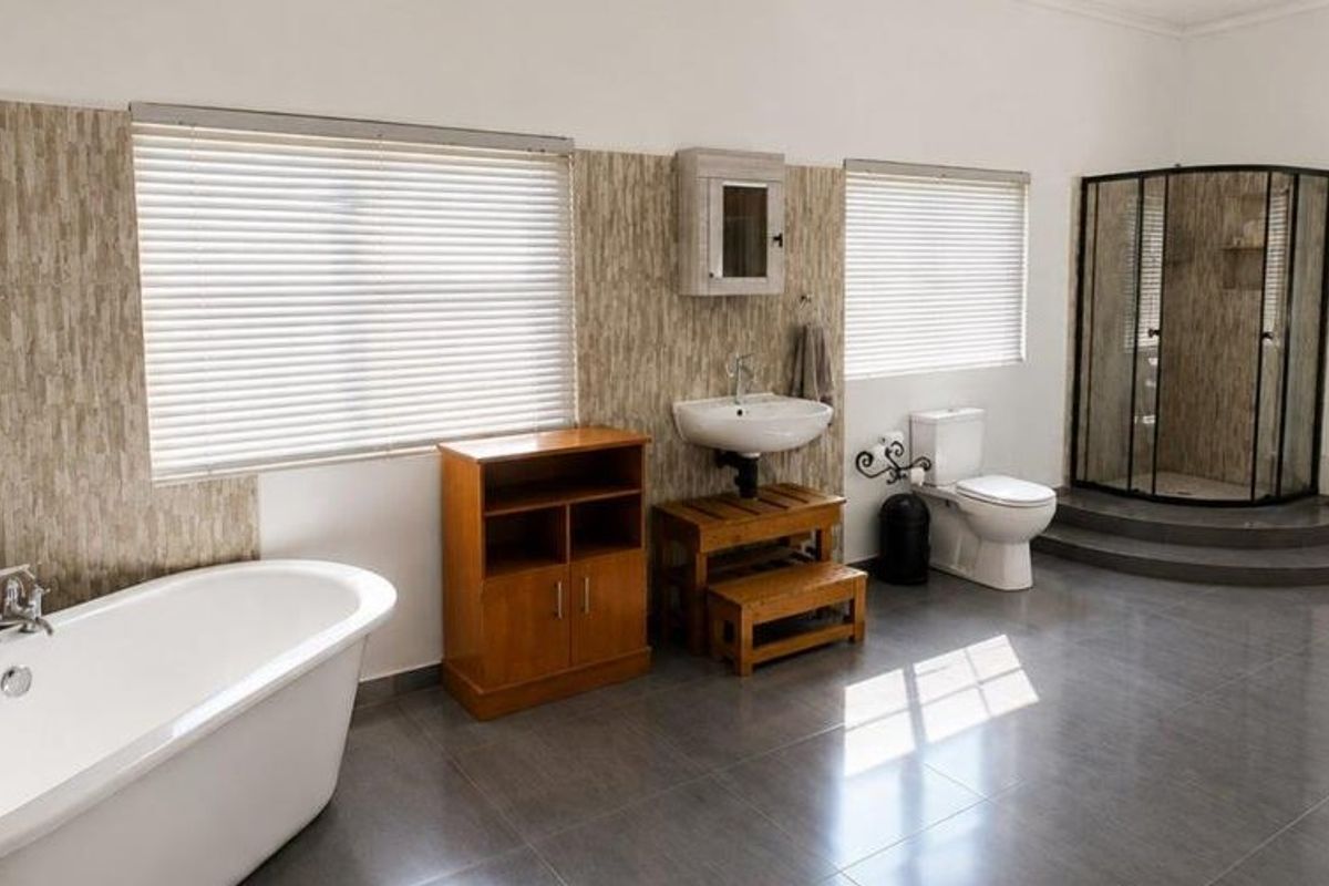 Spacious bathroom featuring a freestanding bathtub, corner shower enclosure, wall-mounted basin, and modern tiled finishes with neutral tones.