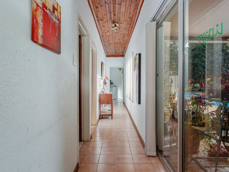 A bright hallway featuring tiled flooring and a timber-paneled ceiling, with large sliding glass doors providing natural light and access to the outdoor area.