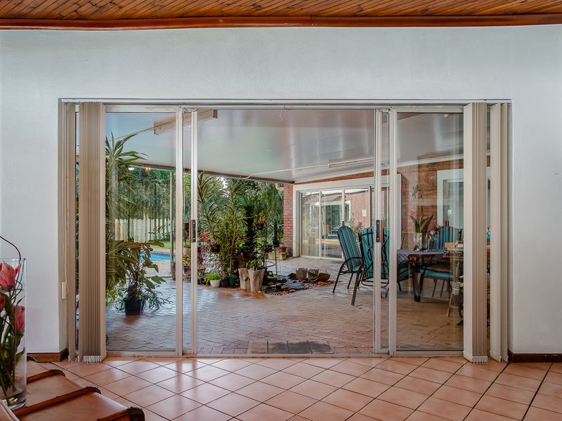 A view from an interior space looking out through large sliding glass doors onto a covered brick-paved patio area.