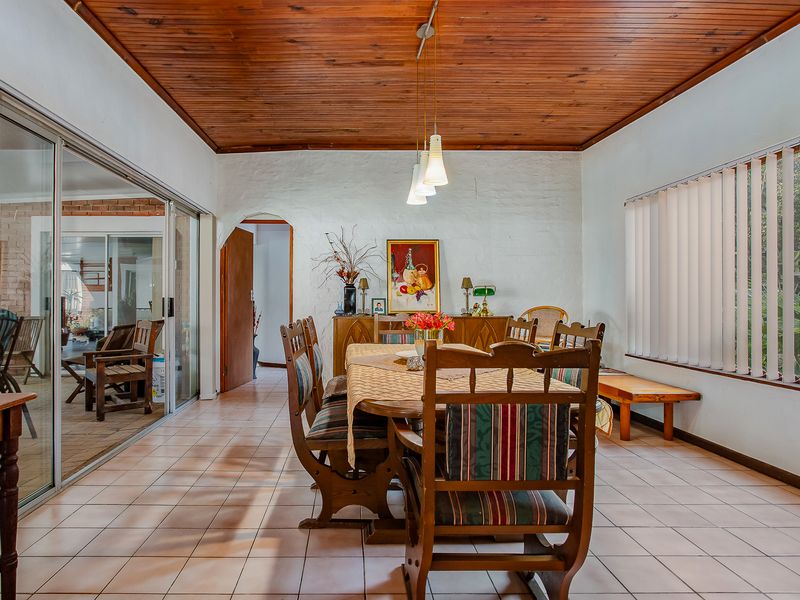 Dining room featuring a warm timber tongue and groove ceiling, ceramic tiled flooring, and large sliding glass doors providing access to the patio area.