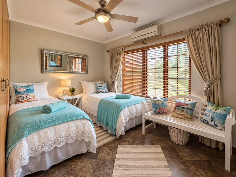 A well-maintained bedroom featuring tiled flooring, a ceiling fan, split-system air conditioning, and wooden venetian blinds.
