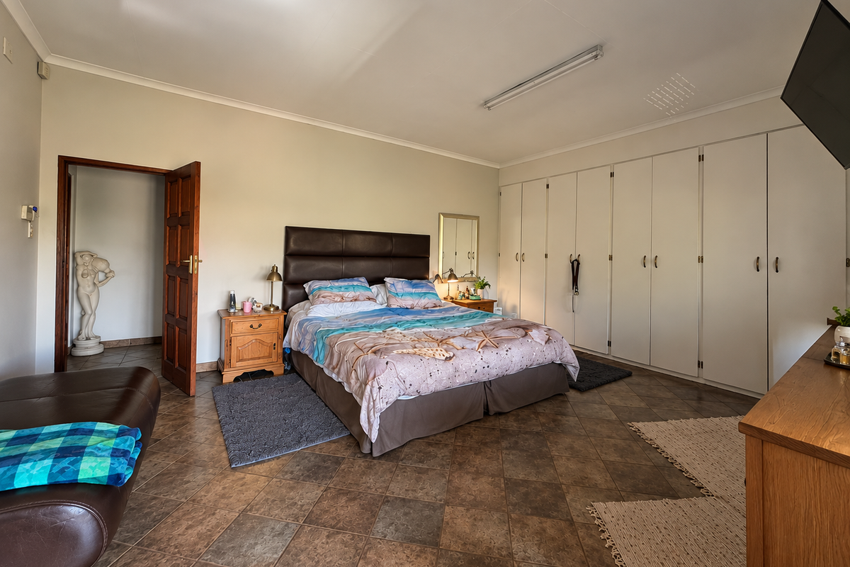 Spacious bedroom featuring extensive built-in cupboards, tiled flooring, and direct access to an adjoining room.